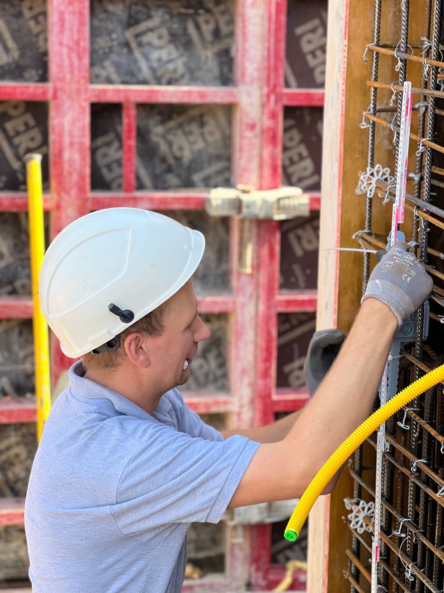 Elektriker von Swiss Green Life verlegt ein gelbes Rohr an der Schalung auf einer Baustelle