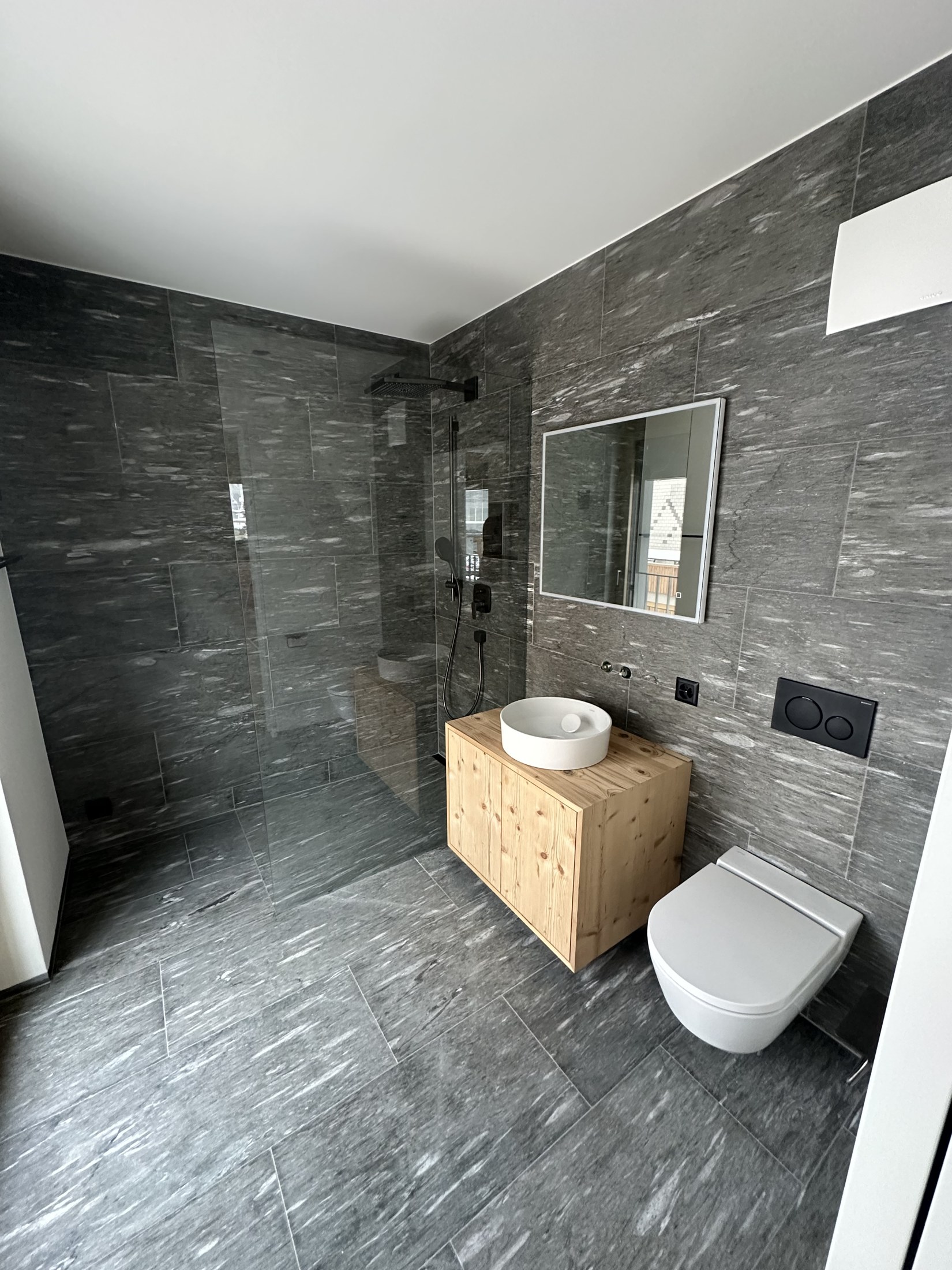 Dusche und Waschtisch mit dunklen Wandplatten